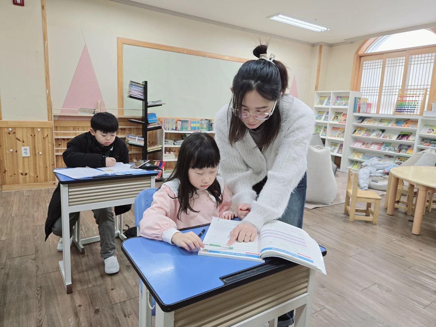 영어책을 함께 보며 지도하는 선생님과 초등 수업 학생